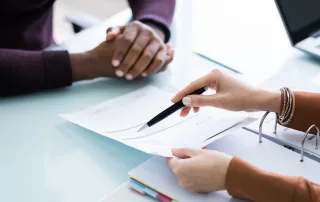 Two people look at tax documents while sitting at a table.